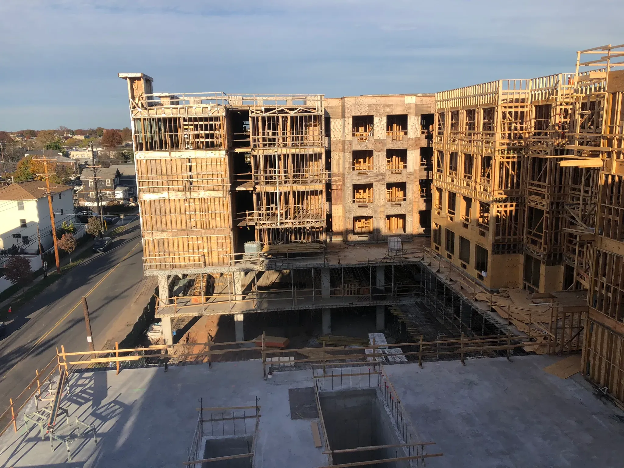 Multi-story mixed-use building under construction with wood framing, open courtyard, and concrete podium structure below.
